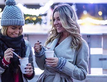 Two girlfriends smiling and enjoying hot cocoa together in Mammoth
