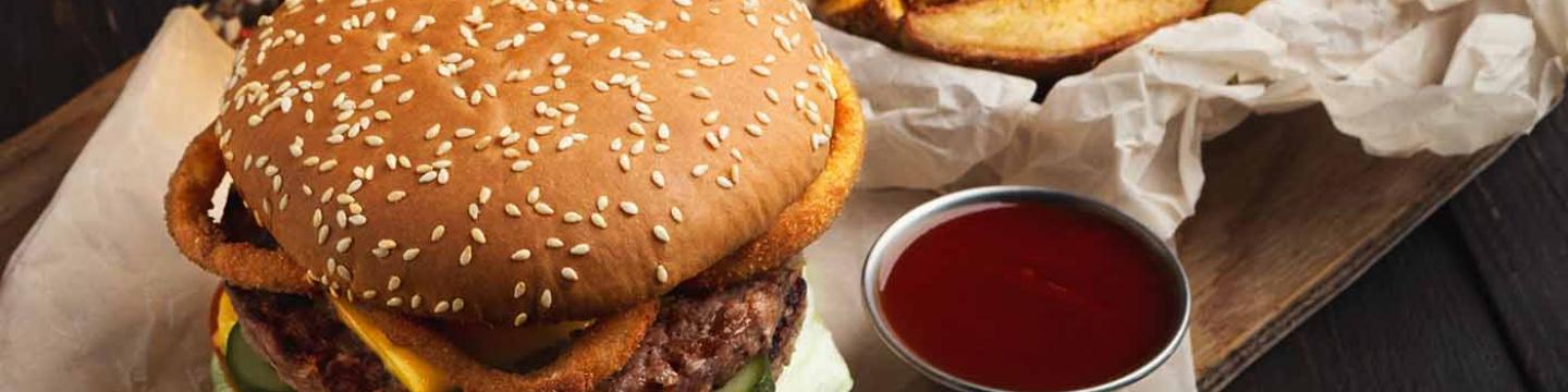 A glass of beer with a burger and fries