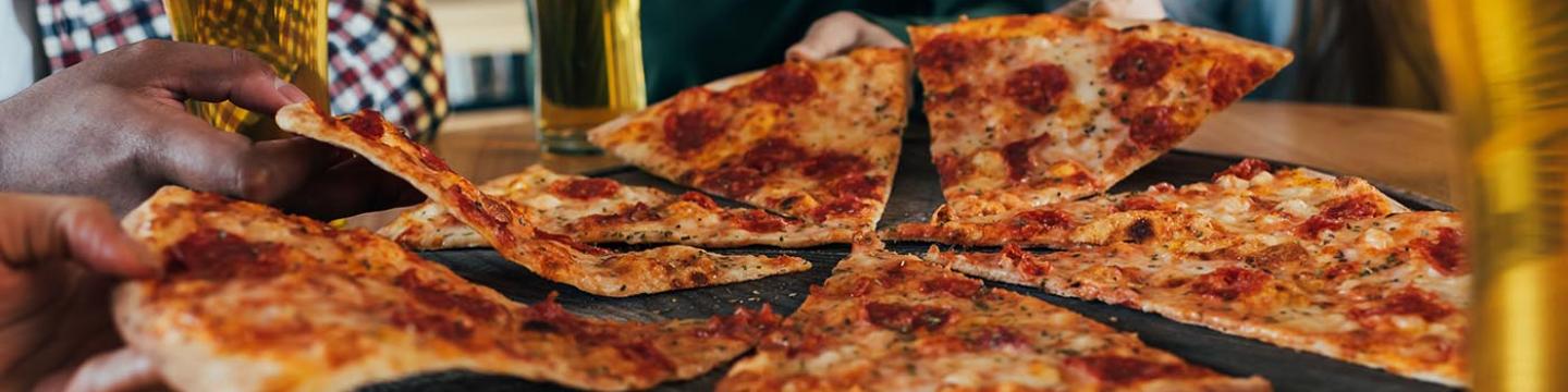 Friends sharing a fresh pizza and beer