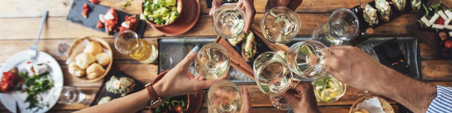 Friends making a toast with wine over a table full of food