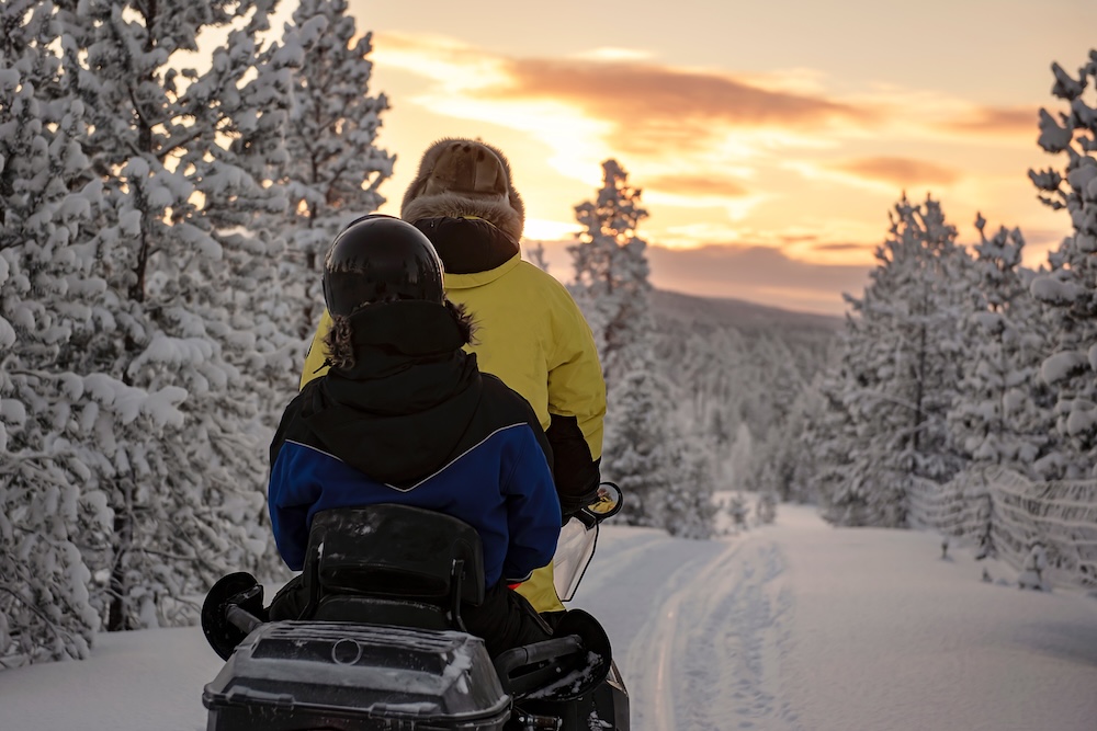 2 people riding on a snowmobile.