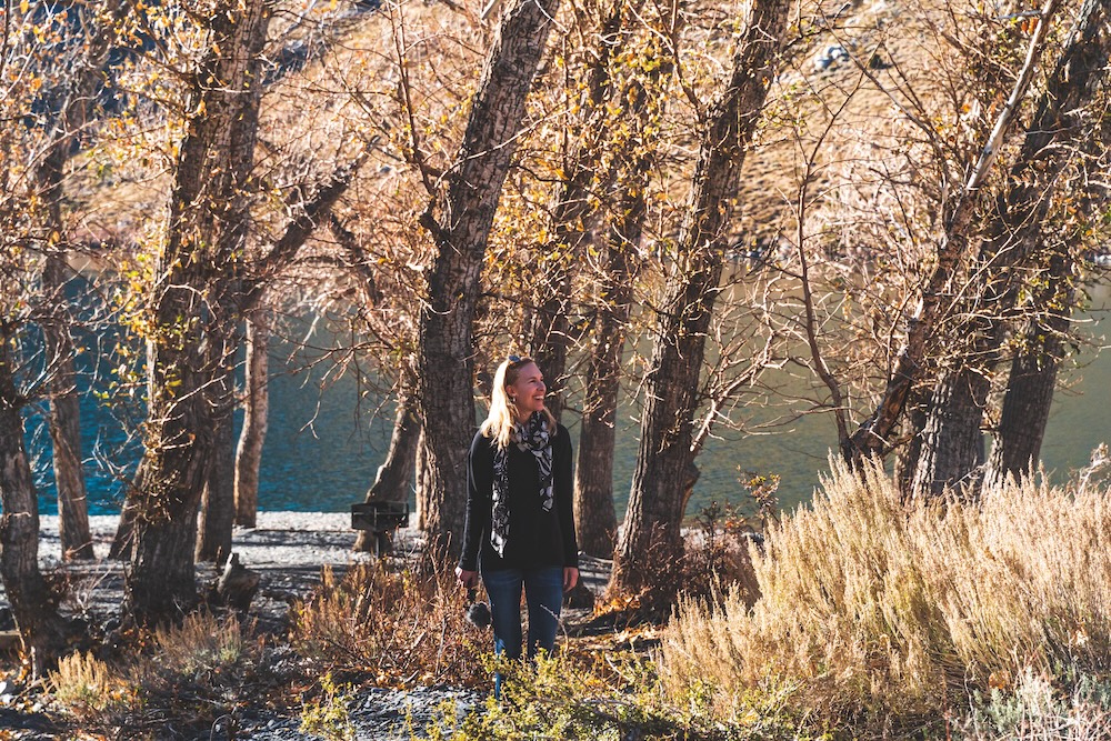 Traveler exploring mountain lake against trees in fall.