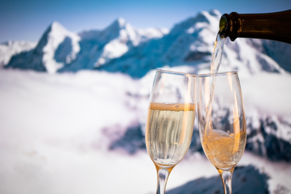 Champagne glasses and snowy peaks in background New Year.