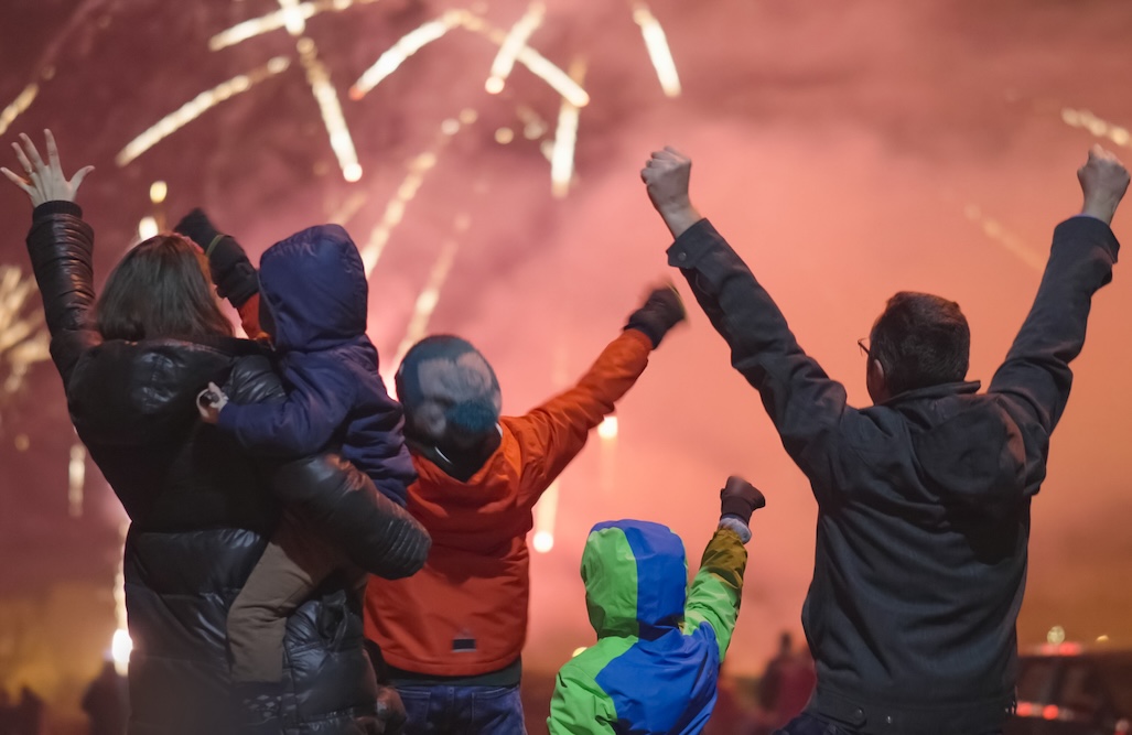 Excited happy family with kids watch and enjoy the New Year Eve night fireworks show.