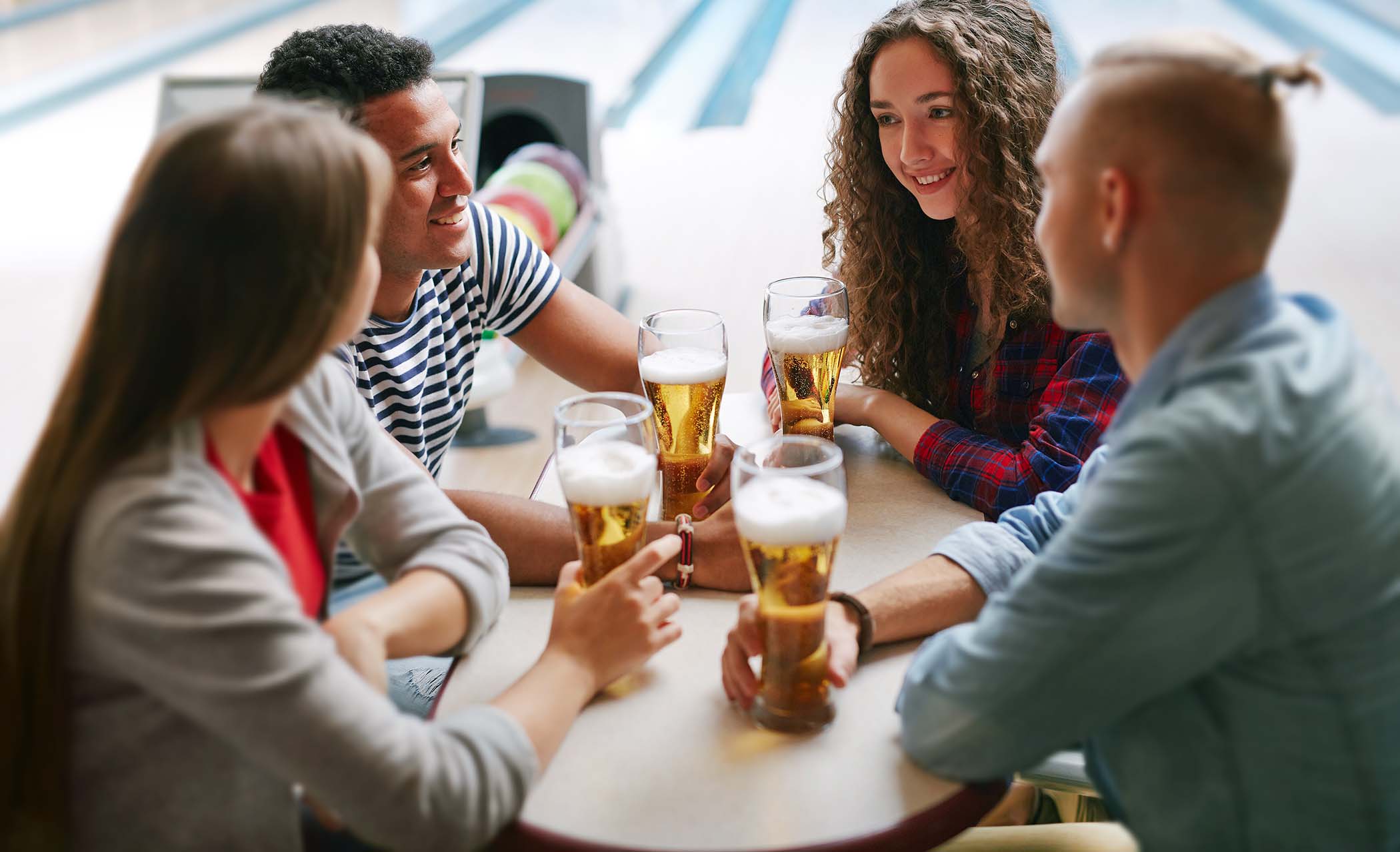 Friends drinking beer lane-side at a bowling alley