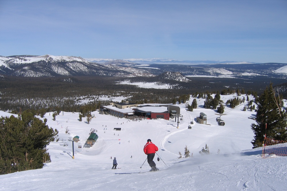 Person skiing downhill with red jacket in the mountains at ski resort