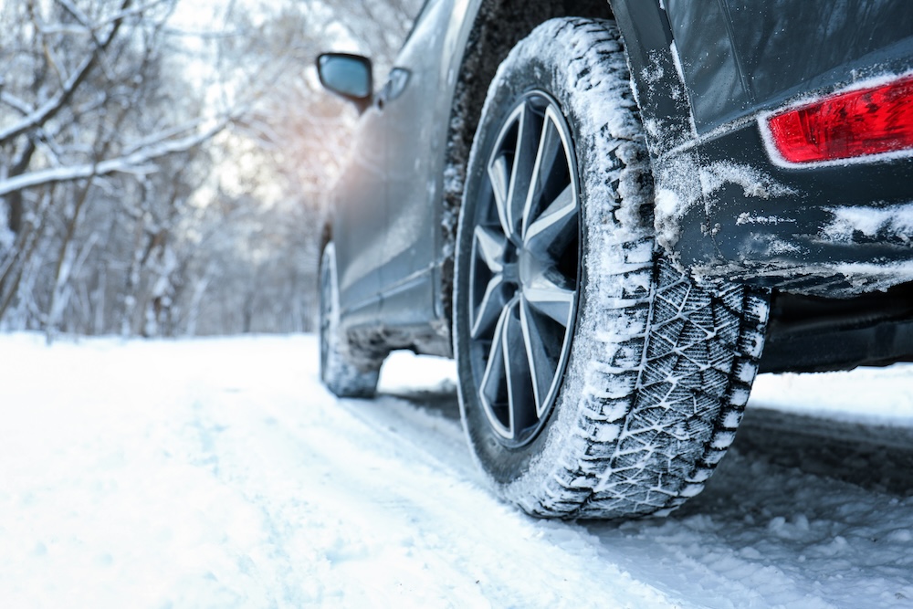 Snowy country road with car on winter day.