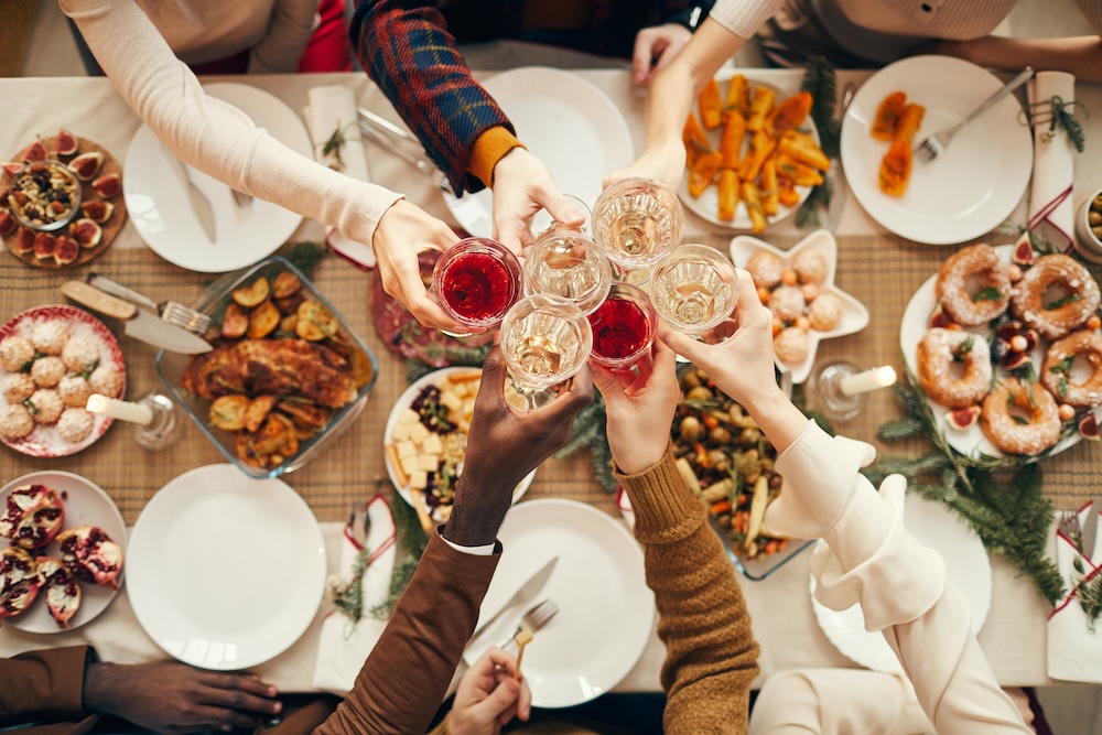 Top view background of people raising glasses over festive dinner table while celebrating Christmas with friends and family.